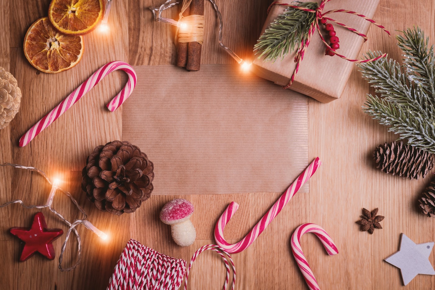 Rustic Christmas flat lay with pine, candy canes, cinnamon, and fairy lights on wood